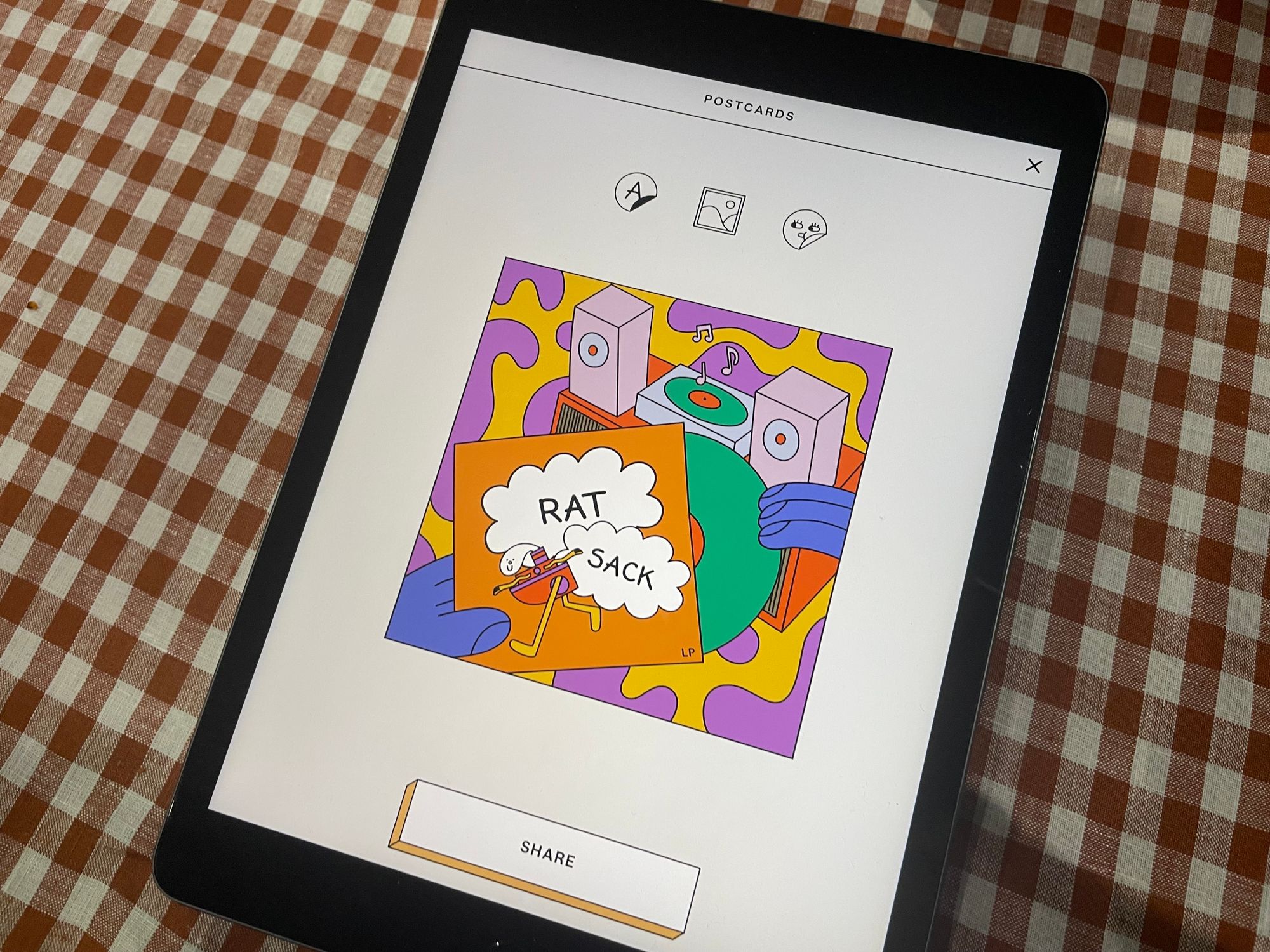 A tablet with a colourful postcard from the game that says "Rat Sack" among cartoons.