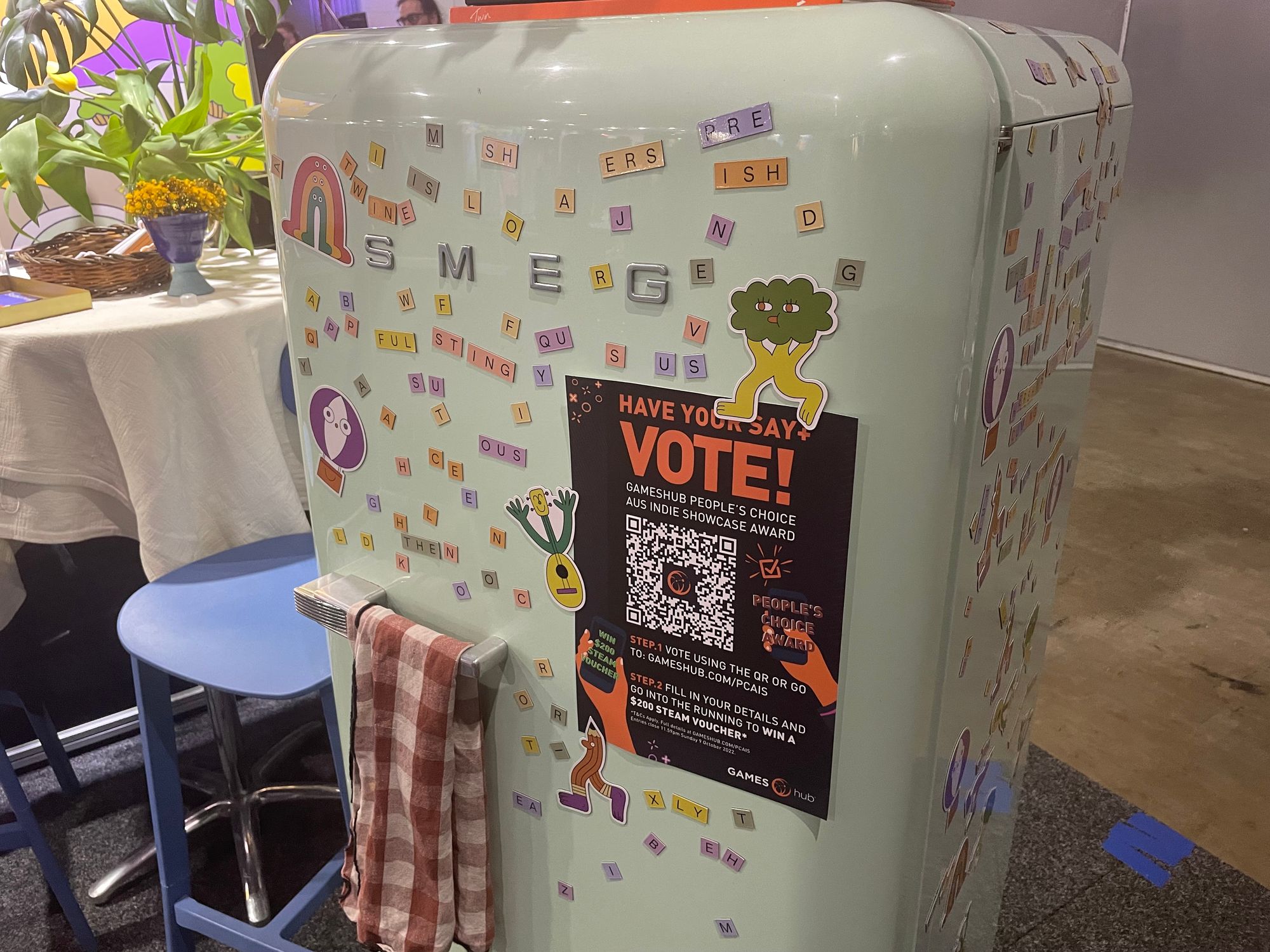 A pastel green retro fridge covered in Gubbins magnets at the game's booth during PAX Australia 2022.