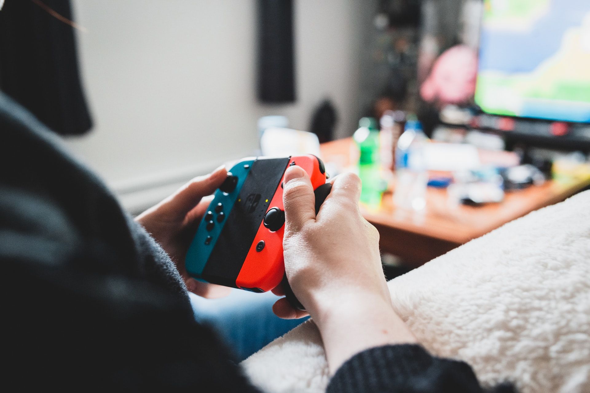 A person playing the Nintendo Switch with the Joycons mounted on a controller base.