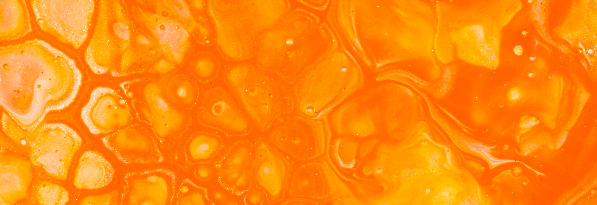 A close shot of orange paint poured over a canvas.