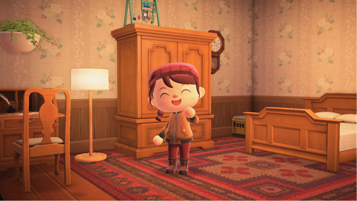 Screenshot of Animal Crossing: New Horizons. The player character has long brown hair in a braid. She wears a red pageboy cap, brown leather jacket, red pants, and brown boots. She stands in a room with floral wallpaper, antique wooden furniture, and a red rug. The lighting is soft.