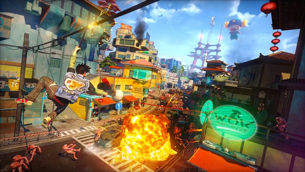 A screenshot from Sunset Overdrive; a man in a denim vest shoots a fireball into a busy street while ziplining down a power c